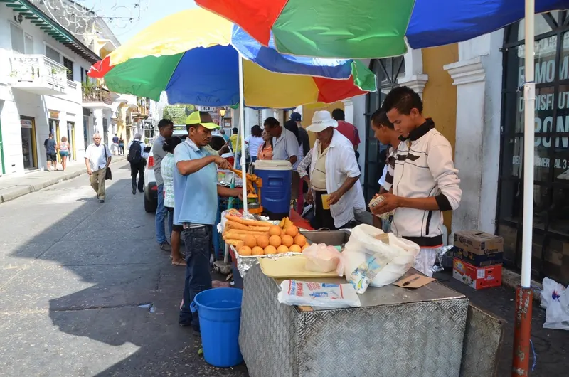 Un puesto de comida callejera bajo sombrillas de colores en Getsemaní